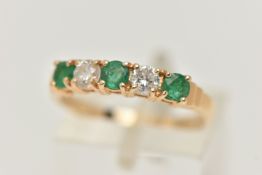 A YELLOW METAL EMERALD AND DIAMOND HALF ETERNTIY RING, set with two round brilliant cut diamonds,