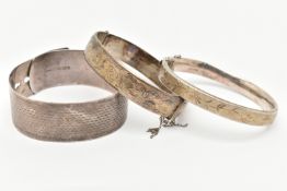 THREE SILVER BANGLES, the first a wide engine turned pattern belt style bangle, hallmarked