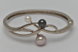 A WHITE METAL HINGED BANGLE, open work design set with three imitation pearls, fitted with a