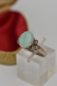 AN OPAL RING, an oval opal, approximate length 10.5mm, prong set in white metal, flanked with six