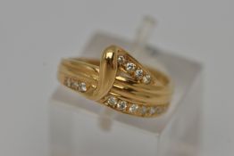 A YELLOW METAL DIAMOND SET RING, abstract band ring, grain set with fourteen round brilliant cut