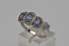 A 9CT GOLD GEM SET RING, three oval cut diamonds, prong set with a surround of grain set round