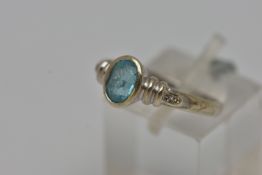 A WHITE METAL GEM SET RING, an oval cut topaz, bezel set, flanked with four round brilliant cut