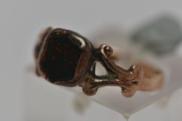 A ROSE METAL SIGNET RING, inlay set with a shield form bloodstone, scrolling detail to the