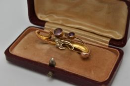AN EARLY 20TH CENTURY BROOCH, a scrolling yellow gold brooch set with two circular cut amethysts and