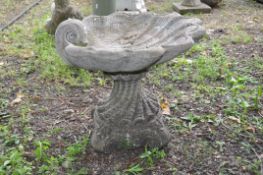 A MODERN COMPOSITE BIRD BATH in the form of a clam shell atop a spiralled linen fold base 51cm in