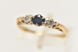 A YELLOW METAL GEM SET RING, set with a central circular cut blue sapphire, flanked with two