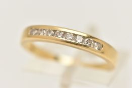 A YELLOW METAL DIAMOND BAND RING, eight round brilliant cut diamonds, channel set in yellow metal,