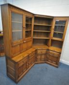 LUCIAN ERCOLANI, AN ELM AND BEECH CORNER WALL CABINET, fitted with an arrangement of glazed doors,