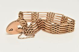 A YELLOW METAL GATE BRACELET, a five bar bracelet fitted with a heart padlock clasp, clasp stamped
