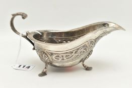 AN IRISH GEORGE V SILVER SAUCE BOAT, with Celtic embossed design, raised on three shell capped feet,