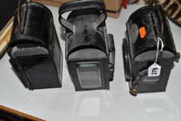 THREE ASSORTED PARAFFIN/OIL LAMPS, of square form with loop handle to top, one with red lens to