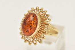 A DRESS RING, designed as a central oval imitation amber cabochon within a collet setting to the