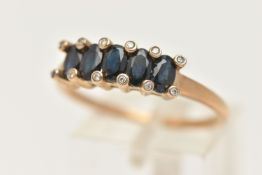 A 9CT GOLD SAPPHIRE AND DIAMOND RING, designed as a row of five oval cut deep blue sapphires, shared