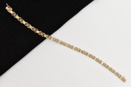 A 9CT GOLD PERIDOT LINE BRACELET, designed as a series of seventeen oval cut peridots, each in a