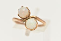 AN EARLY 20TH CENTURY TOI ET MOI RING, two round cabochon opals prong set in yellow metal, stamped