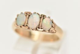 A THREE STONE OPAL RING, three oval opals prong set in yellow metal, scroll detail to the shoulders,
