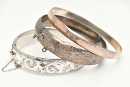 THREE BANGLES, to include two silver hinged bangles, both with foliate patterns, push piece clasps