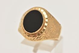 A YELLOW METAL SIGNET RING, inlay set with oval cut onyx, etched and textured detail to the shank,