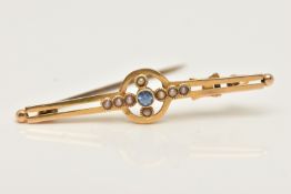 A YELLOW METAL GEM SET BROOCH, set with a central small light blue circular cut sapphire milgrain
