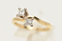 AN 18CT GOLD DIAMOND CROSS OVER RING, designed as two princess cut diamonds each in a four claw