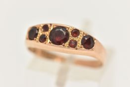 A LATE VICTORIAN 15CT GOLD GARNET RING, set with seven circular cut garnets, to a polished band,