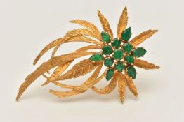 A YELLOW METAL EMERALD SET SPRAY BROOCH, textured spray of leaves, set with a cluster of circular