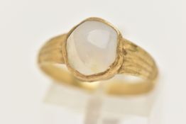 A YELLOW METAL QUARTZ RING, set with a quartz cabochon stone, rough collet set to textured shoulders
