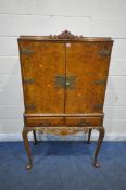A QUEEN ANNE STYLE WALNUT DRINKS CABINET, with a foliate crest, the double doors enclosing a