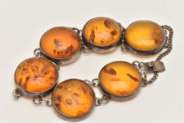 AN AMBER BRACELET, the links designed as circular cabochons of heat treated amber in collet settings