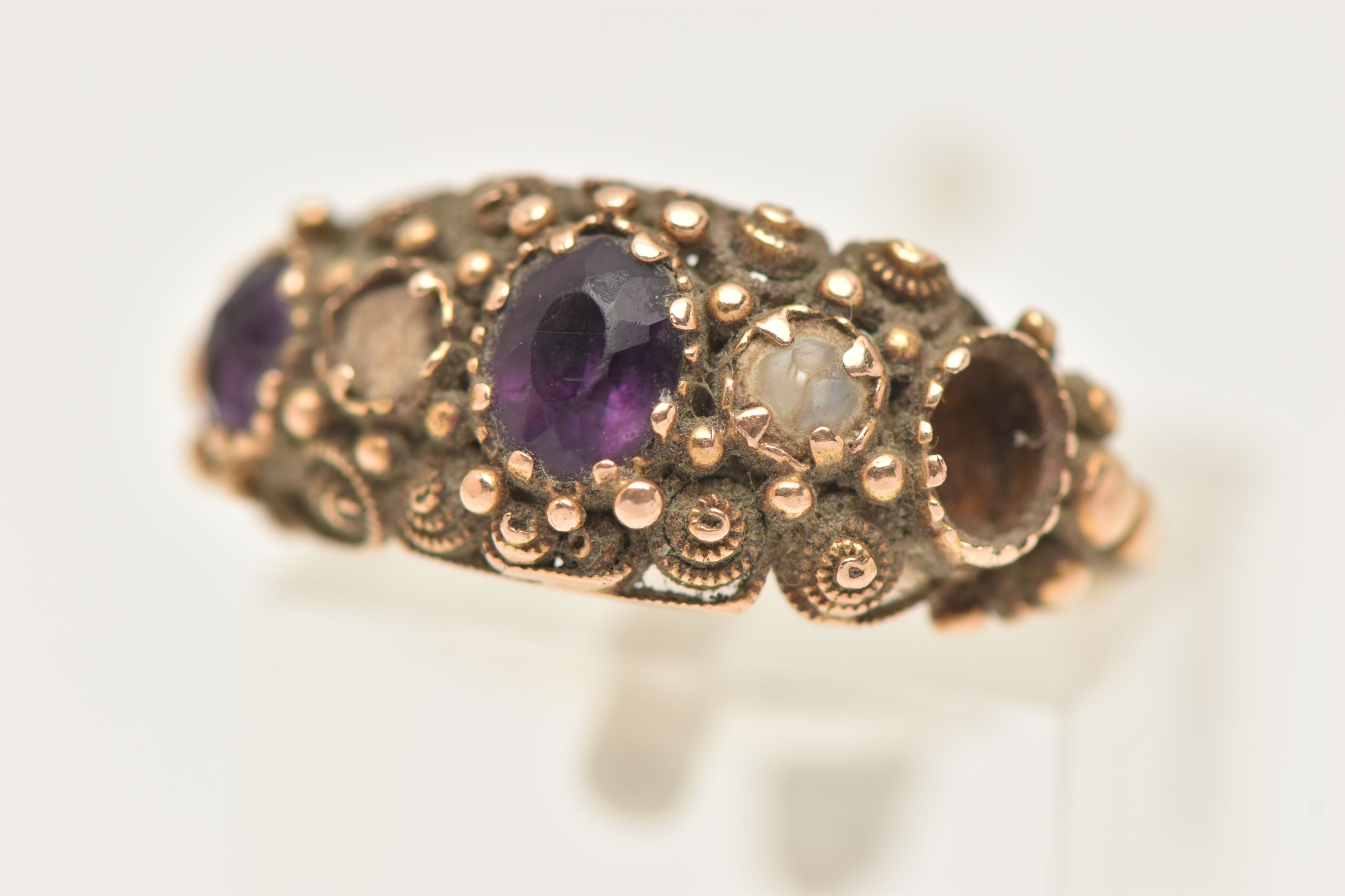 A YELLOW METAL GEM SET RING, AF set with two oval cut amethysts (one missing) and a single split