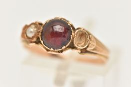 A YELLOW METAL GEM SET RING, AF set with a central garnet cabochon, collet set and flanked with a