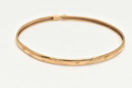 A YELLOW METAL BANGLE, with a repeating textured pattern, fitted with a safety clasp, approximate
