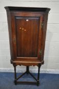 A GEORGIAN AND LATER OAK CORNER CUPBOARD ON STAND, with a single door, raised on turned front