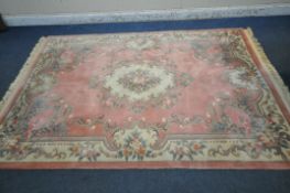 A LARGE PINK GROUND CHINESE WOOLLEN RUG, with a central medallion, repeating foliate patterns,