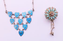 An enamel and silver flower brooch and an enamel necklace with heart shaped linked pendants.