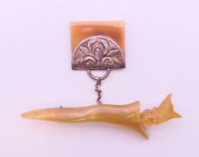 An Arabian horn and silver brooch (possible rhino horn) in the form of a dagger and bag. 7 cm long.