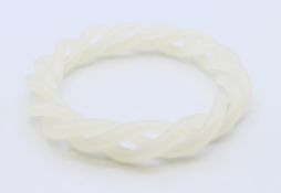 A white jade triple twist bangle. 6 cm internal diameter, 9 cm external diameter.