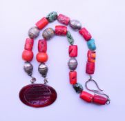 A Persian silver, coral and turquoise pendant necklace.