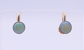 A pair of 9 ct gold and opal earrings. Each 6 mm diameter.