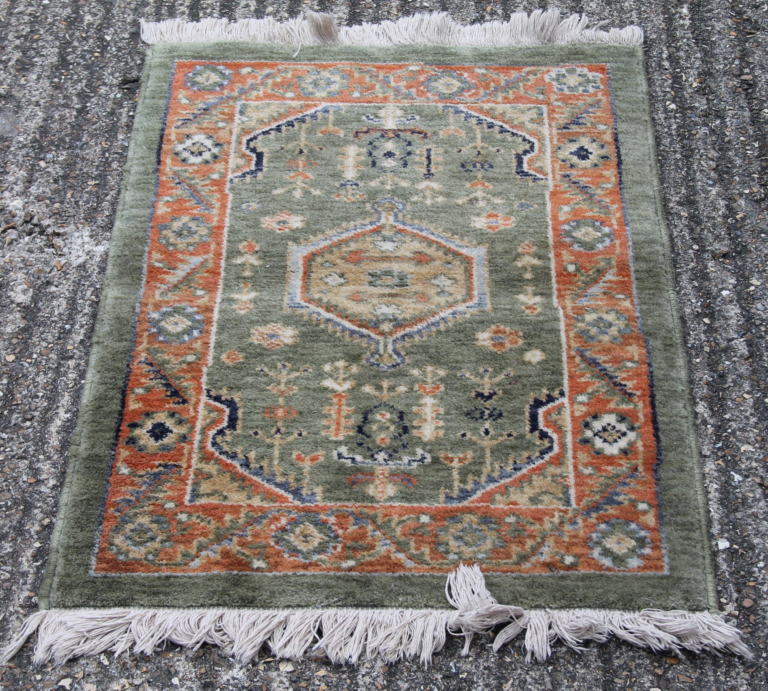 A small green ground rug. 60 x 95 cm.