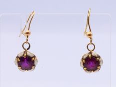 A pair of unmarked gold and enamel earrings. 1 cm diameter.