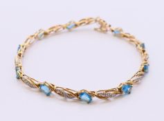 A 9 ct gold, diamond and blue topaz line bracelet. 19 cm long. 7.4 grammes total weight.