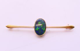 A 15 ct gold black opal bar brooch. 6.5 cm long, opal 1.5 cm x 1 cm. 4.6 grammes.