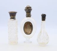 Three silver topped glass scent bottles. The largest 10 cm high.