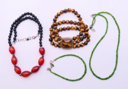 A green bead necklace and matching bracelet, a tiger's eye bead bracelet and another bead necklace.