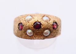 A 9 ct gold garnet and seed pearl ring. Ring size R. 4.2 grammes total weight.