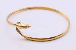 A 9 ct gold dolphin form bangle bracelet. 6.5 cm diameter. 6.4 grammes total weight.