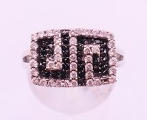 A 9 ct white gold black and white diamond Greek key pattern ring. Ring size N/O. 4.
