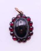 A garnet pendant. 2 cm high excluding suspension loop.